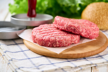 Raw handmade minced beef burger patties on wooden table, selective focus.