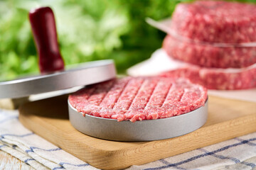 Fresh raw ground beef patties with salt and pepper made in a burger press on a cutting board. uniform patties cook in burger press.