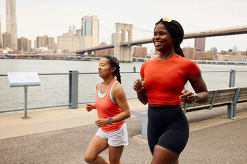 Women jog by the East River