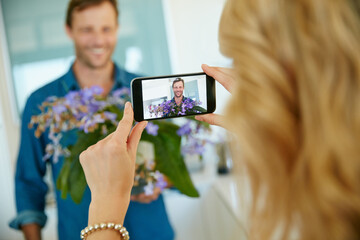 Phone, capture and couple in home with flowers, relationship and connection in digital memories. Tech, happy man or woman in house with bouquet, loving gift or romantic post for social media update.