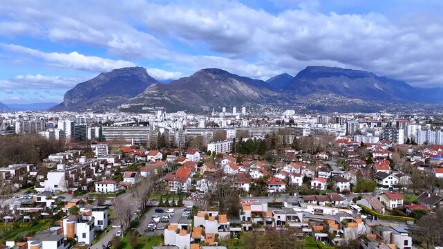 Low drone view of Grenoble suburb red roof houses with Alps and clouds 
