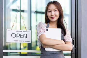 Female owner of coffee shop or restaurant turning round sign to open. Smiling young asian woman owner, employee retail coffee shop woman hand in setting sign board to open for welcome customer, reopen