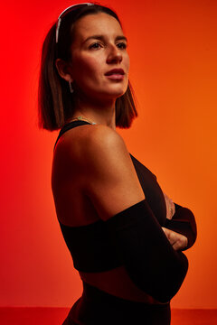 Confident woman posing against a vibrant orange background