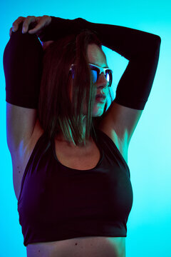 Model poses in black athletic wear against a blue backdrop