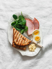 Delicious breakfast, brunch - grilled bread, boiled egg, spinach, ham on a light background, top view