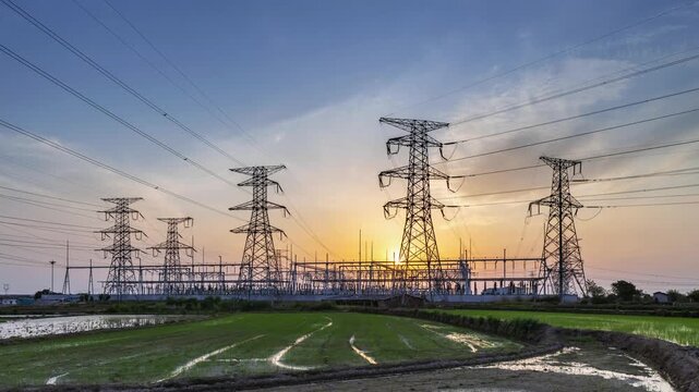 time-lapse of a power substation with high-voltage transmission towers and rural fields at sunset, energy infrastructure landscape in twilight glow