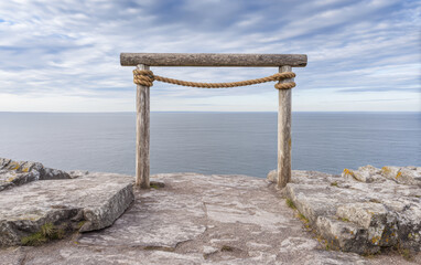 Viewpoint overlooking the ocean with wooden frame near rocky shoreline during cloudy day in coastal area