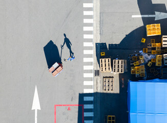 Aerial Logistics Yard with Worker, Pallets, and Marked Zones
