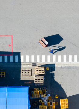 Worker Pulling Cart with Long Shadow Factory Warehouse