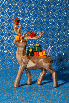 a glitter reindeer holding multiple colorful presents