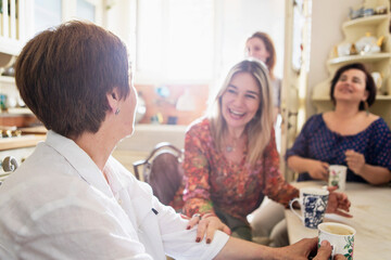 Friends enjoying laughter and coffee in a cozy kitchen setting