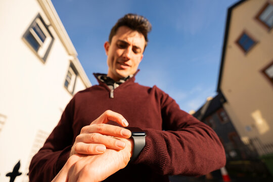 Smartly Dressed Man Interacts With Smartwatch on Sidewalk Near House