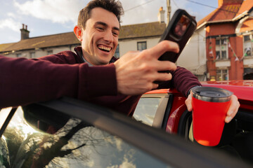 Man Happily Checks Mobile App in Parked Red Car During Trip