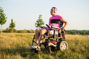 Disabled man sitting in a wheelchair listening to music while spending time in nature.