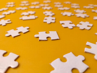 Fototapeta premium Pieces of a jigsaw puzzle scattered across a yellow background