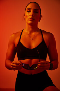 Confident athlete poses with sunglasses against a warm backdrop