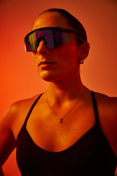 A woman stands confidently, wearing sleek reflective sunglasses