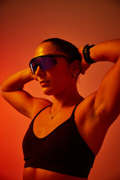 Strong athlete poses confidently with sunglasses under warm ligh