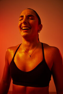 Joyful woman exercising under warm light in fitness studio