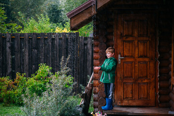 Boy enjoys nature by a wooden cottage during rain