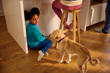 Little girl plays with a dog on the kitchen floor