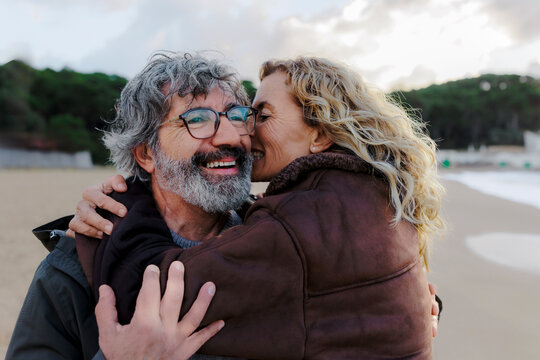 Mature couple sharing intimate moment with a whisper on the beach