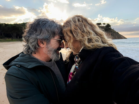 Mature couple sharing intimate selfie moment on beach