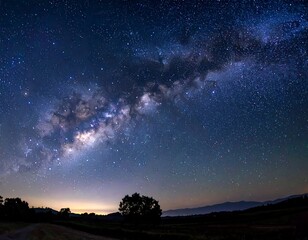 Fototapeta premium Deep space vista of a star-filled galaxy above dark, silhouetted landscape