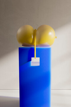 3D render of compressed balloons tied by string on blue pedestal