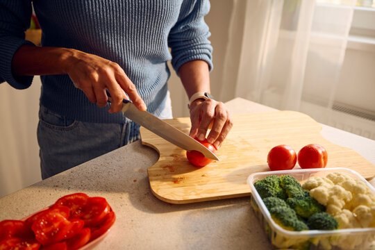 Woman chops tomatoes on the countertop