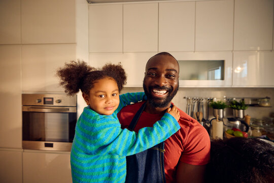 Happy man carries his daughter while cooking