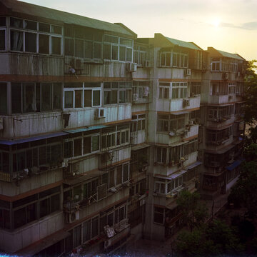 The sun sets behind an old apartment building.