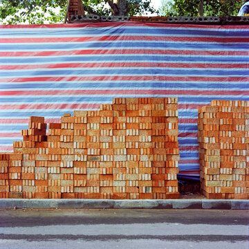 Stacks of bricks piled up in front of a blue and red striped tarp