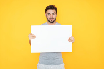 Handsome man holding empty board isolated on studio background. Guy showing blank signboard with copyspace. Idea offer. Your advertisement. Blank advertising board with empty space for text, mock up.