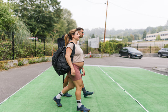 Pregnant woman and her partner walking to fitness training