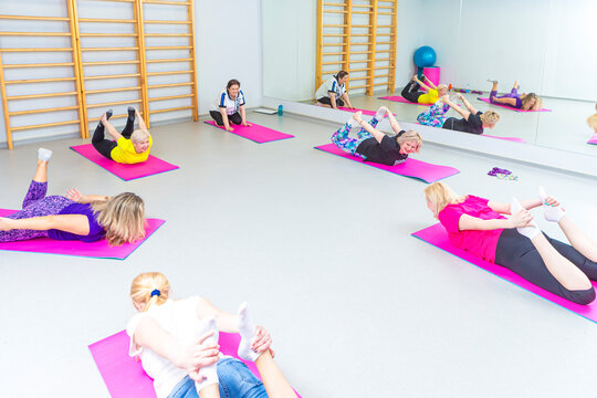 Mature Women at Bodyflex People Practicing Stretching Yoga Exercice Standing on Mats With Body Flex Bending in Room As Peaceful Focused Emotional Therapy Concept.
