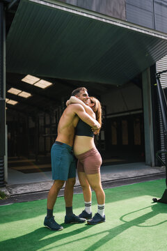 Expecting couple hugging after functional workout session