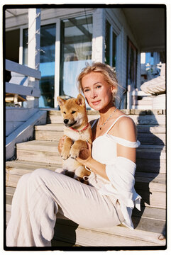 Woman sitting with her Shiba Inu dog on the porch of her house 