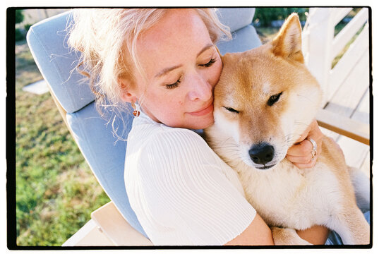 Film closeup portrait of a woman tenderly hugging her Shiba Inu dog