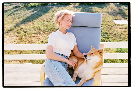 Film photo of happy woman sitting outside with her Shiba Inu dog