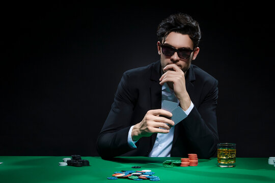 Thoughtful Risky Caucasian Young Handsome Pocker Player Staking and Betting To Win At Pocker Table With Chips And Cards to Depict Casino and Gambling Concepts.