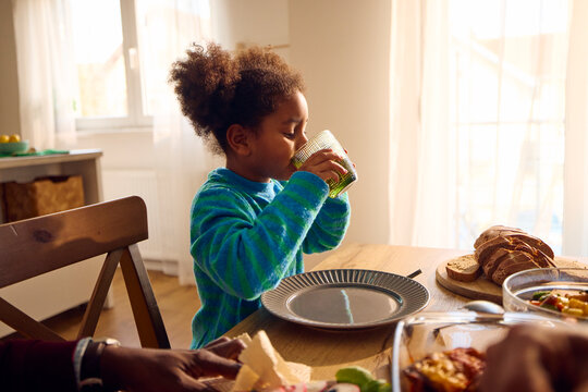 Little girl drinks water at home