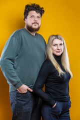 Lifestyle Concepts. Young Positive Caucasian Smiling Happy Adorable Couple As Friendly Family Man And Woman Casual Clothing Together Embracing Cuddle Isolated on Seamless Yellow