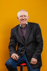 Happy Caucasian Mature Man in Jacket over Yellow Background posing with smile