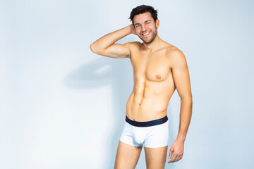 Good Looking Laughing Positive Sensual Caucasian Handsome Brunet Man Posing With Lifted Hand in Underware Against White