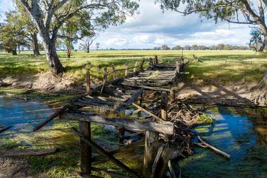 Weathered timber bridge collapsing over a quiet country creek