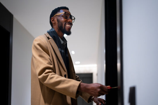 Man smiling while unlocking a modern apartment door in the evening