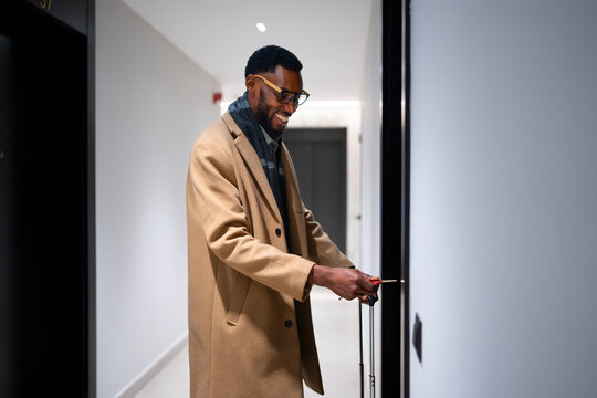 Man in coat unlocking door in modern hallway