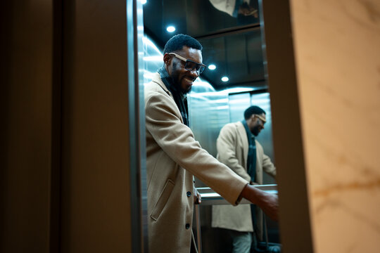 Man smiling while entering an elevator in a modern building