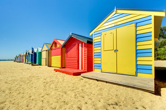 Bright beach huts lined up in vivid colours under a clear blue sky.